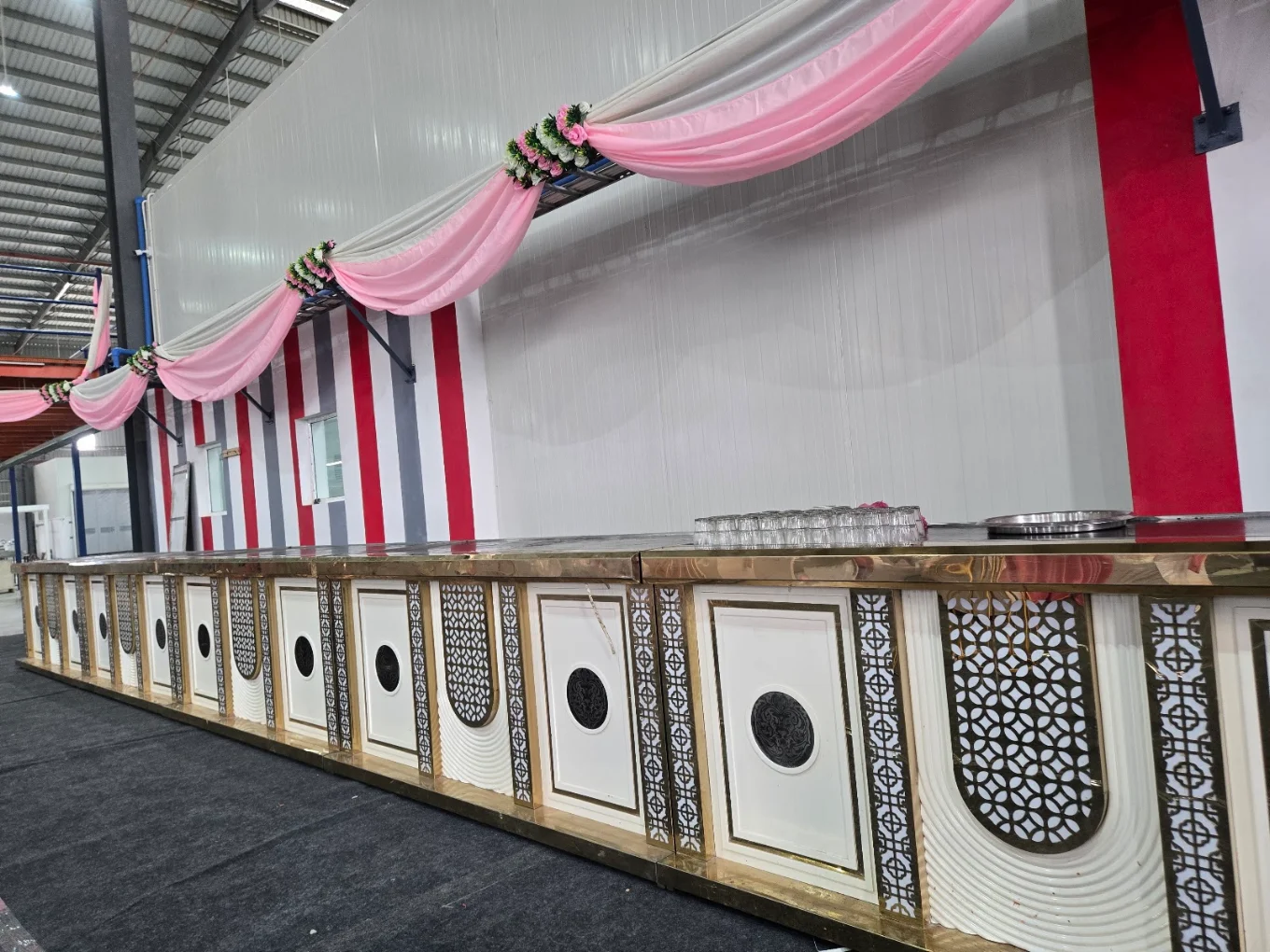Ornate gold and white long buffet counter with pink draping